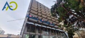 کلایمر برقی دو موتوره در حال کار روی نمای یک برج بلند برای سیمان کاری نما