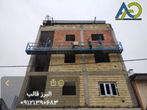 عمال مجهزون بمعدات السلامة (هارنس) أثناء العمل على المنصة المعلّقة للواجهات