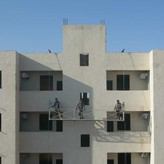 فريق تنظيف واجهات يعمل على منصة معلقة لتنظيف واجهة برج زجاجي مرتفع