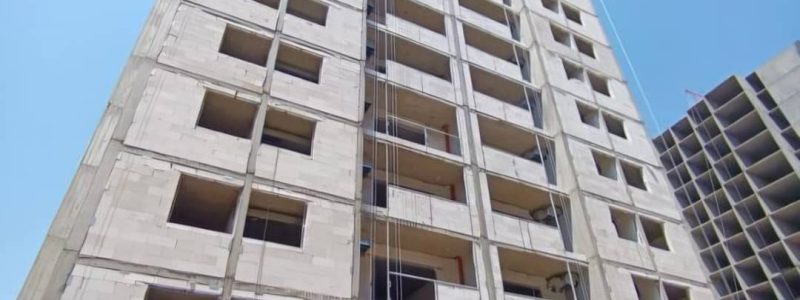 نمای یک برج مدرن با دستگاه کلایمر یا بالابر نما در حال کار برای بازسازی